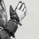 Homme portant des gants de moto gris chauffants sur un fond gris