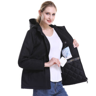 Femme blonde portant un manteau noir chauffant avec sa batterie en main sur fond blanc