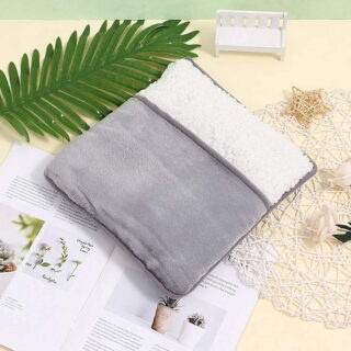 Chauffe pieds gris et blanc avec une feuille verte au dessus et des journaux en dessous