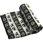 plaid chauffant à rayures noir et blanc avec des motifs montagnards de flocons de neige et de cerfs, partiellement plié/roulé, sur fond blanc