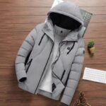blouson chauffant gris avec batterie poser sur une table marron