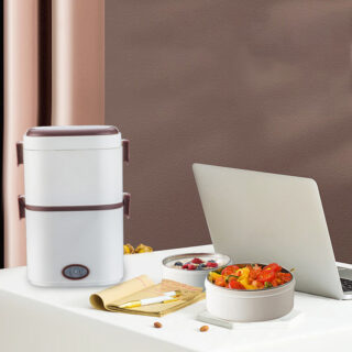 On voit un Tupperware chauffant blanc double niveaux sur un bureau près d'un ordinateur